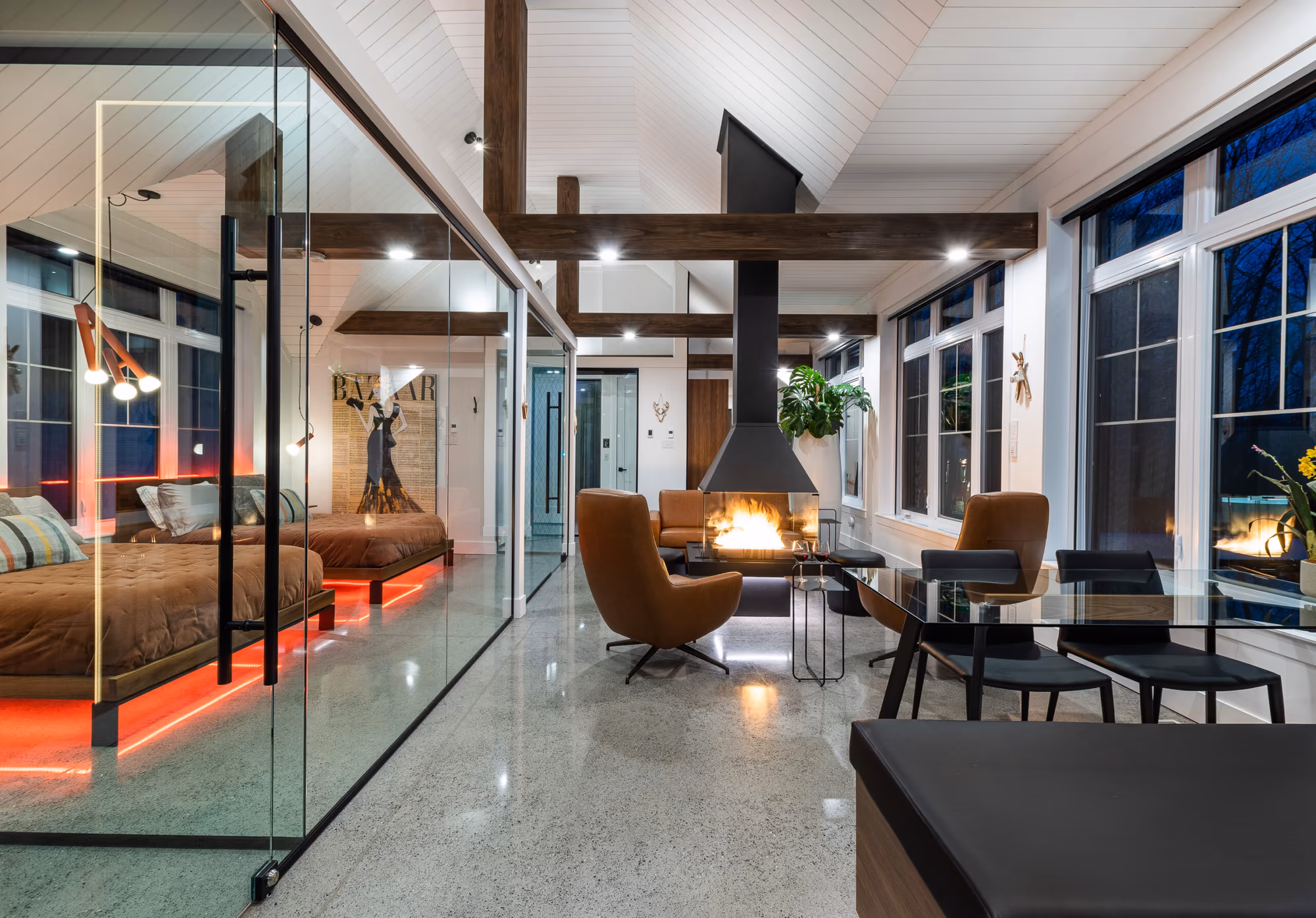La suite au crépuscule : chambre vitrée, foyer central et coin repas en enfilade